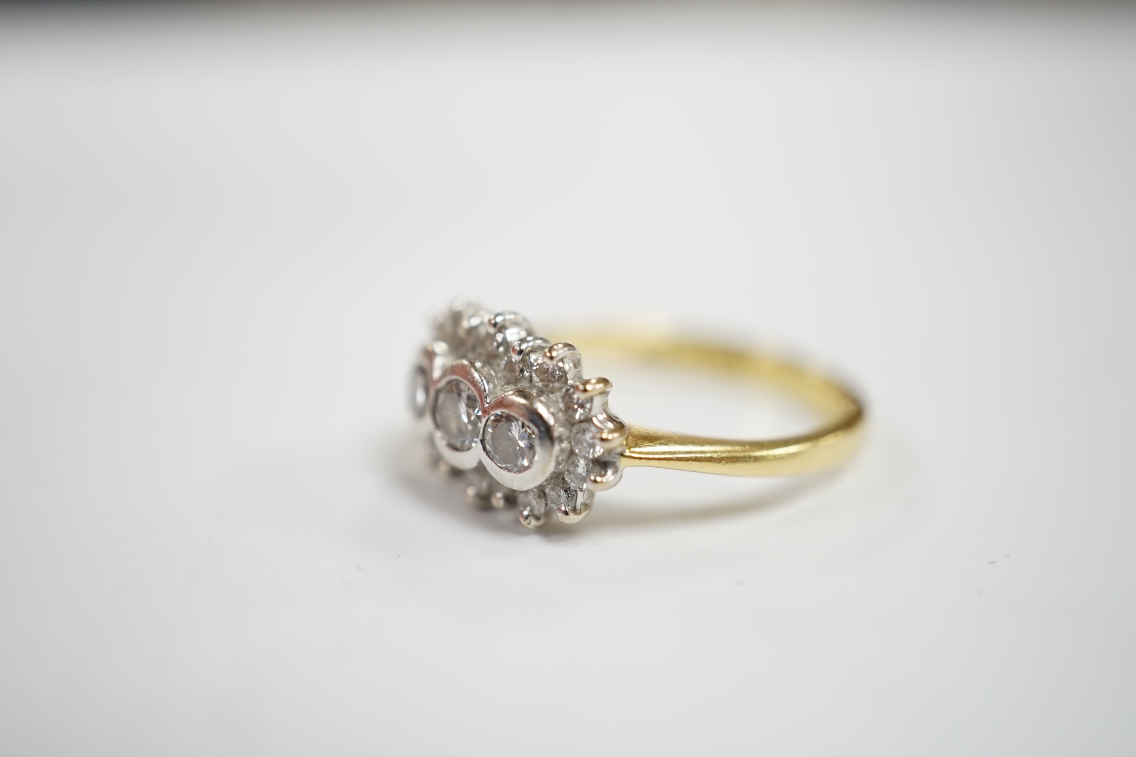 A modern 18ct gold and collet set three stone diamond ring, with diamond chip set border, size J/K, gross weight 4.6 grams.